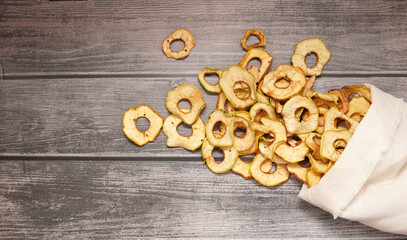 dried apples are poured into rings from a bag on a wooden table.