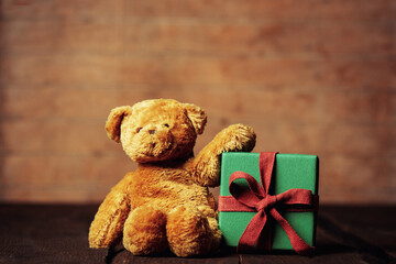Teddy bear and holiday gift on wooden table nad background