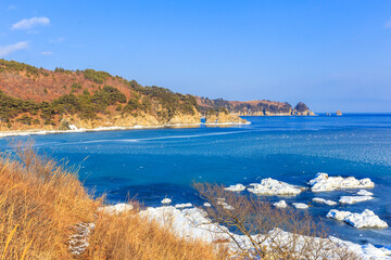 Far Eastern Marine Reserve in winter. Picturesque rocky coast, overgrown with conifers of low...