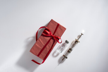 red vaccine gift with syringe on white background Creative Coronavirus or 2019-nCoV or COVID-19...