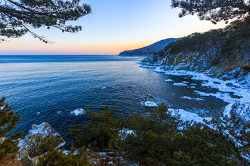 Far Eastern Marine Reserve in winter. Picturesque rocky coast, overgrown with conifers of low...