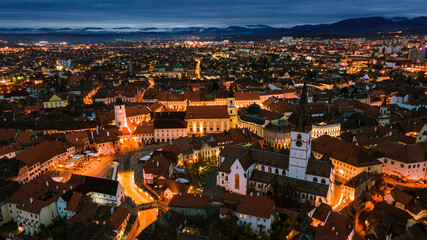 Obraz premium Aerial photography of Sibiu city center shot from a drone at sunset with city lights on. View from above Sibiu, Romania. Landscape photography taken from above Sibiu, Romania.