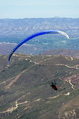Paragliding Pilot Flying a Paraglider - 468452915