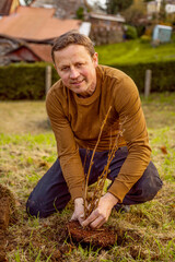 Naklejka na ściany i meble Man plants tree in the garden. Nature, environment and ecology concept.