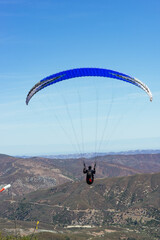 Paragliding Pilot Flying a Paraglider - 468452924