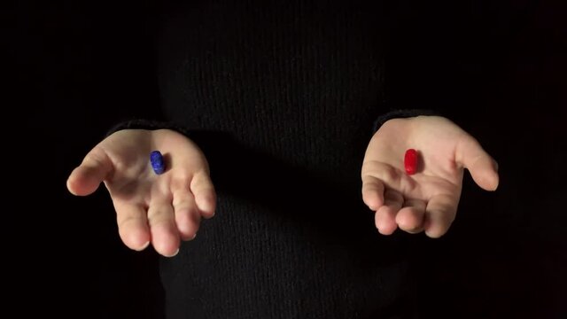 Offering a Red pill or a blue pill. Human hands hold red and blue pills. Dark background. Studio shot 4K footage