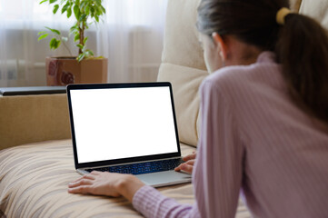 A girl with a laptop lies on the couch. Laptop with blank white display. Selective focusing.