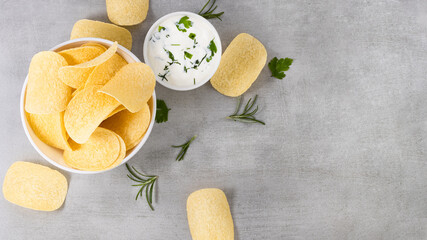 potato chips in a bowl with sauce on a gray background. Top view with copy space