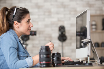 Fototapeta na wymiar woman looking at computer screen while repairing camera lens