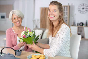 Obraz na płótnie Canvas daughter gives flowers to elderly mother