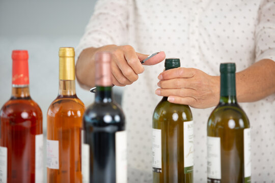 cropped image of a person opening bottles of wine