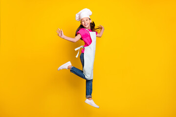 Fototapeta na wymiar Photo of nice glad little small girl jump enjoy flight wear apron cap footwear isolated yellow color background