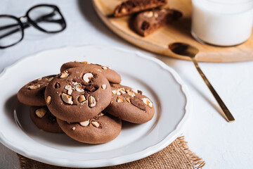 Close up of chocolate cookie with hazelnut and chocolate crumbs positioned on other cookies