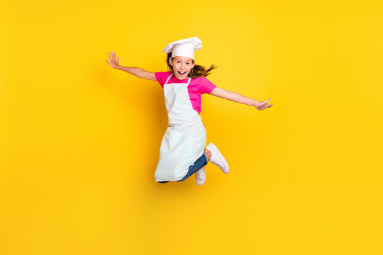 Photo of crazy active inspired carefree small girl jump wear apron cap sneakers isolated yellow color background