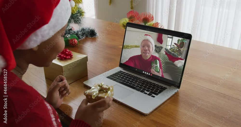 Wall mural African american woman with santa hat using laptop for christmas video call with man on screen