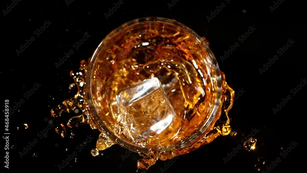 Poster Super slow motion of falling ice cube into whiskey, black background. Speed ramp effect. Filmed on high speed cinema camera, 1000fps