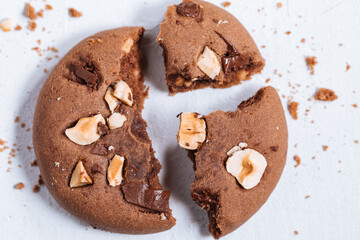 Close up of chocolate cookie with hazelnut and chocolate crumbs positioned on other cookies