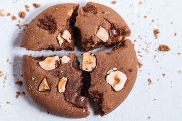 Close up of chocolate cookie with hazelnut and chocolate crumbs positioned on other cookies