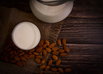 glass of milk, almonds on a wooden background