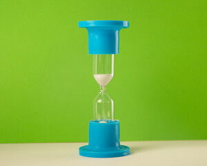 hourglass blue with white sand on a green and white background