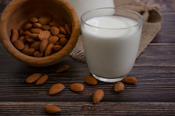glass of milk, almonds on a wooden background