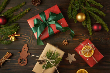 Christmas gifts and branches of Christmas tree on dark wooden background.