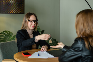 Realtor with glasses passes keys to house or apartment to buyer. Purchase of real estate. Agent hands keys to woman.