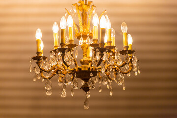 Vintage chandelier golden color with candles shines in a dark room of 