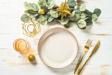 Christmas table setting with eucalyptus leaves and luxury metallic golden decorations. Top view at...