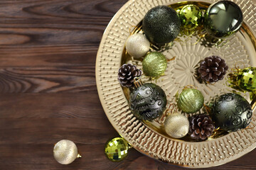 Obraz na płótnie Canvas Golden round tray with Green and gold Christmas tree balls and pine cones on wooden background. Christmas background with copy space. Preparation for the New Year. High quality photo