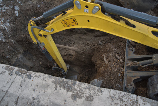Excavator on a construction site digs dirt from a hole.