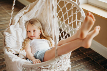 A pretty blonde girl is lying in a hammock with her legs stretched out.