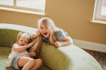 Naughty kids are messing around on the couch. Sisters argue. Girls pull each other's hair.