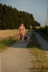 Hundebegegnung, Junge Frau im Kleid mit Hund auf einem Waldweg