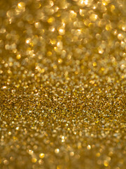 A glittery yellow paper. Golden glitter light bokeh abstract texture. Pattern designs. Sparkle wallpaper for Christmas. Brilliance shimmering sequin background. Party time.
