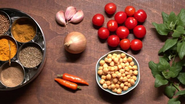 Ingredients and spices for chickpea dish and ready chickpea meal in bowl. Vegan cuisine. Camera slide.