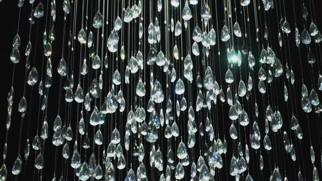 Crystal stones dangle and glisten on black background. Shining crystal chandelier 