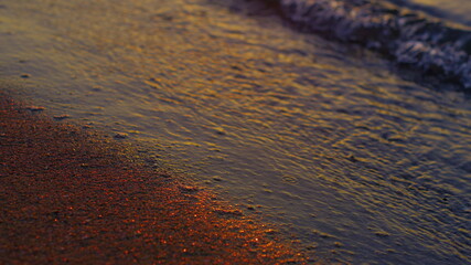 Closeup calm sea waves reflecting bright golden sunset at evening dusk