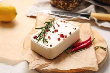 Board with feta cheese and spices on light background