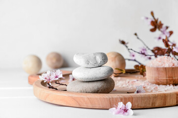 Tray with spa stones with blossoming branch on white background, closeup