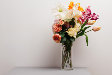 bouquet of flowers in a glass vase on a wooden table. wallpaper for a holiday card or calendar on the occasion of mother's day or international women's day. plants for the interior in the living room.