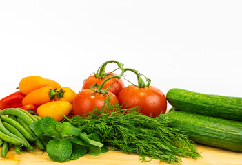 Fresh vegetables and greens on the board, food close up. Group of fresh vegetables on wooden table.