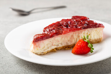 Strawberry glazed cheesecake on white dinnerware on the table.