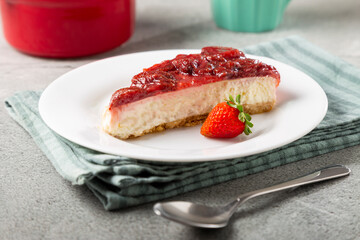 Strawberry glazed cheesecake on white dinnerware on the table.