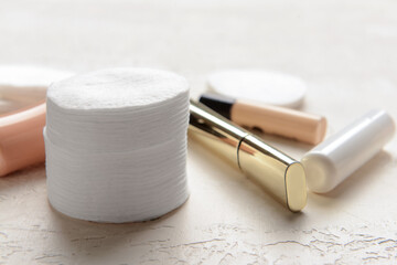 Stack of clean cotton pads and cosmetics on light table, closeup