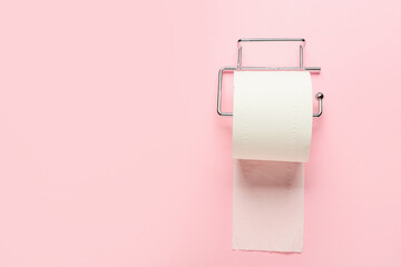 Holder with roll of toilet paper on pink background