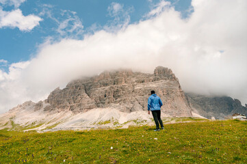 Man in Blue jacket standing on a Dolomite mountain in Italian alps with mountains in background