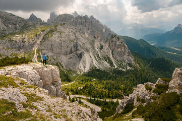 Man in Blue jacket standing on a Dolomite mountain in Italian alps with mountains in background