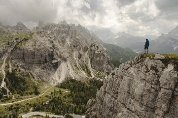 Fototapeta na wymiar Man in Blue jacket standing on a Dolomite mountain in Italian alps with mountains in background