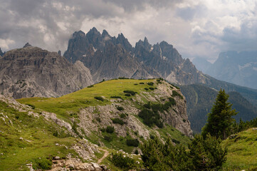 Obraz premium Dolomite mountains in Tre Cime, Italy, with green grass foreground during sunny summer day with blue sky